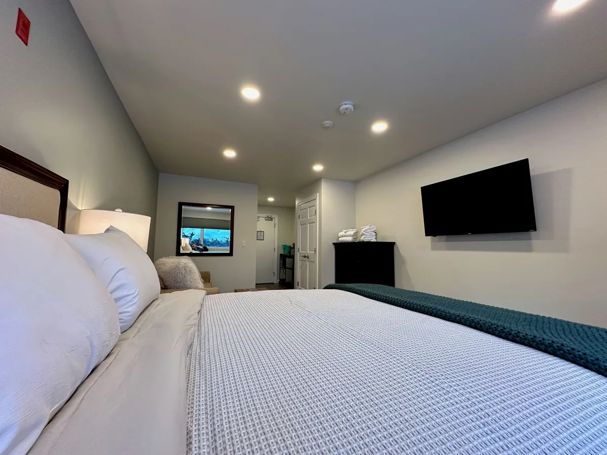A serene bedroom with a comfortable bed, a television for entertainment, a mirror, and a dresser. The space feels welcoming and private, ideal for unwinding after a busy day.